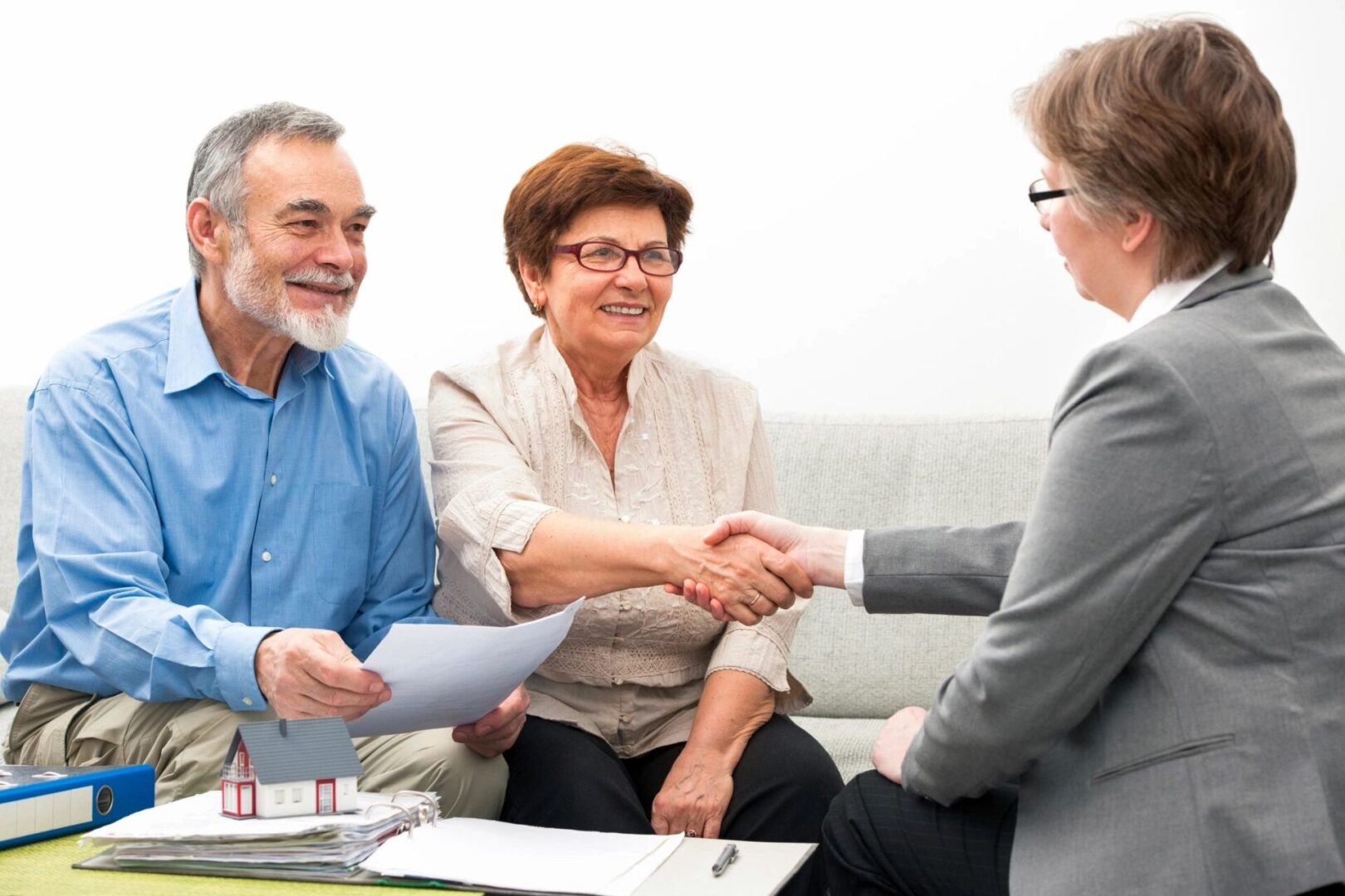 A couple of people shaking hands over papers.