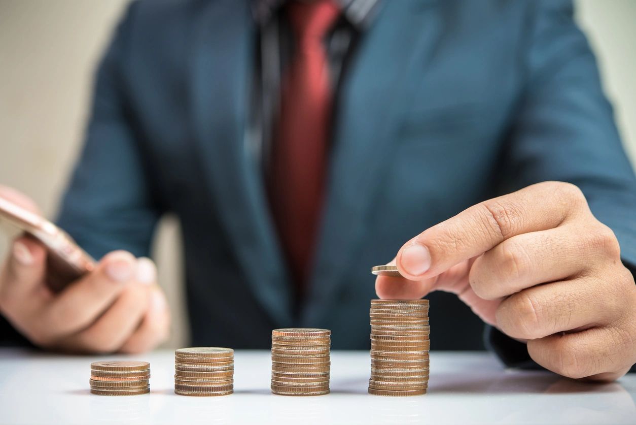 A man in a suit and tie stacking coins.