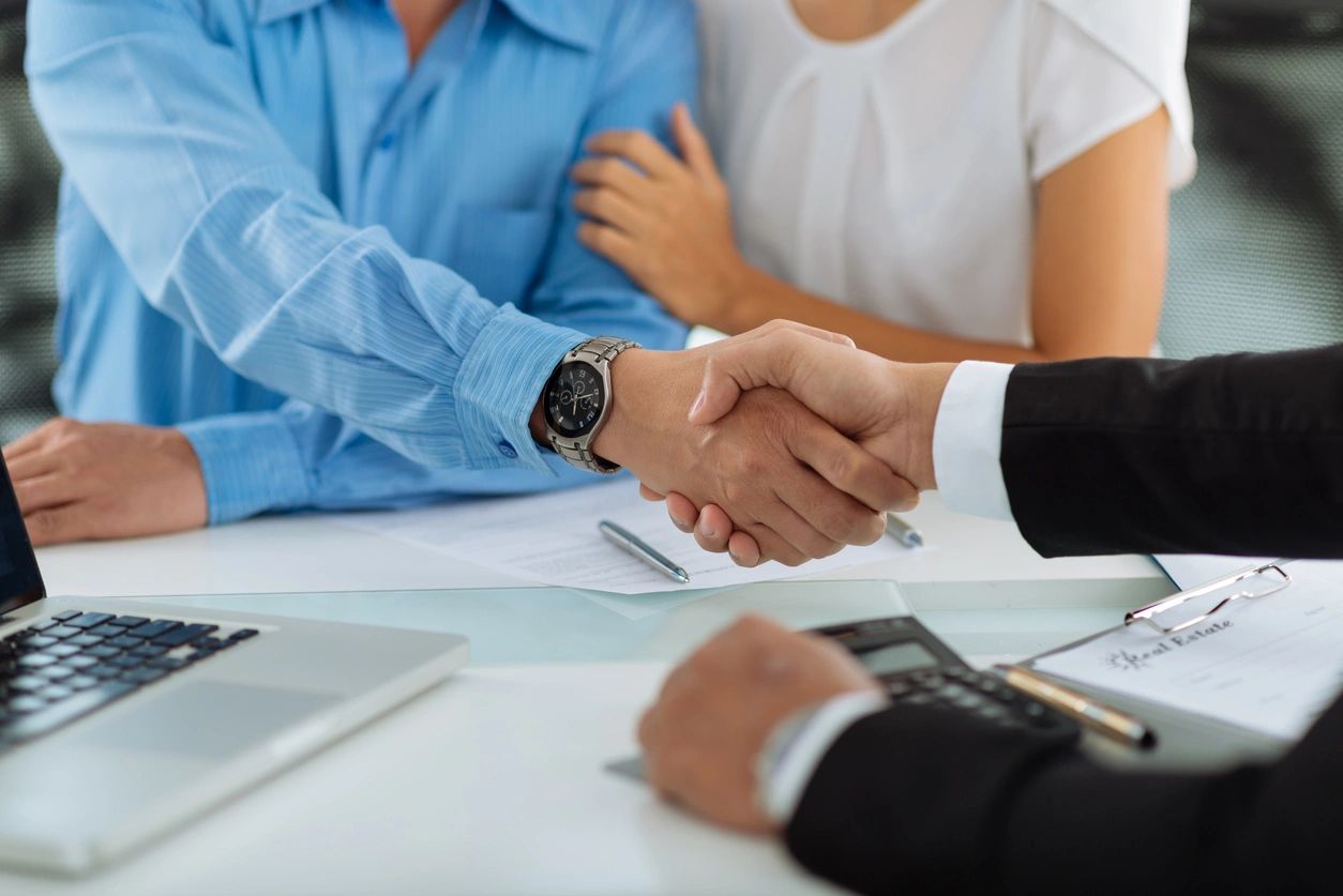 A man shaking hands with another person in front of two other people.